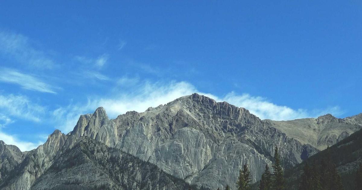 青空の下に広がる山並み。自分の進む道を見渡すイメージ
