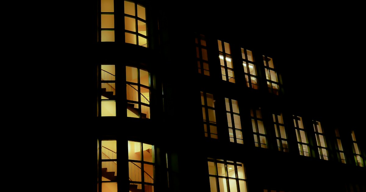 夜に窓の明かりが灯った集合住宅の外観